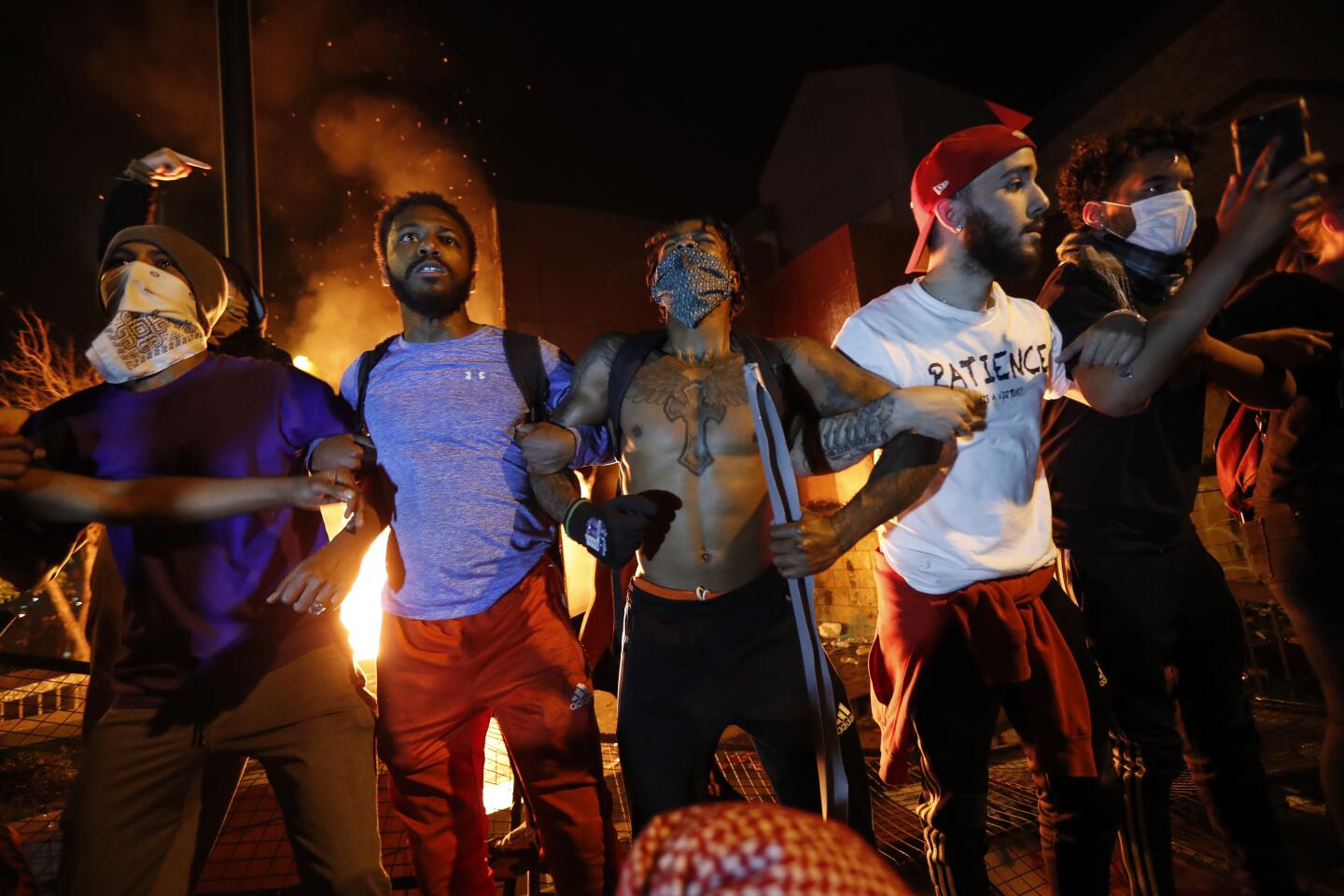 Protesters linked in arms demonstrate outside a burning Minneapolis 3rd Police Precinct.