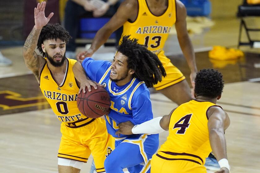 UCLA guard Tyger Campbell, middle, tries to drive between Arizona State guard Holland Woods (0) and forward Kimani Lawrence (4) during the first half of an NCAA college basketball game Thursday, Jan. 7, 2021, in Tempe, Ariz. (AP Photo/Ross D. Franklin)