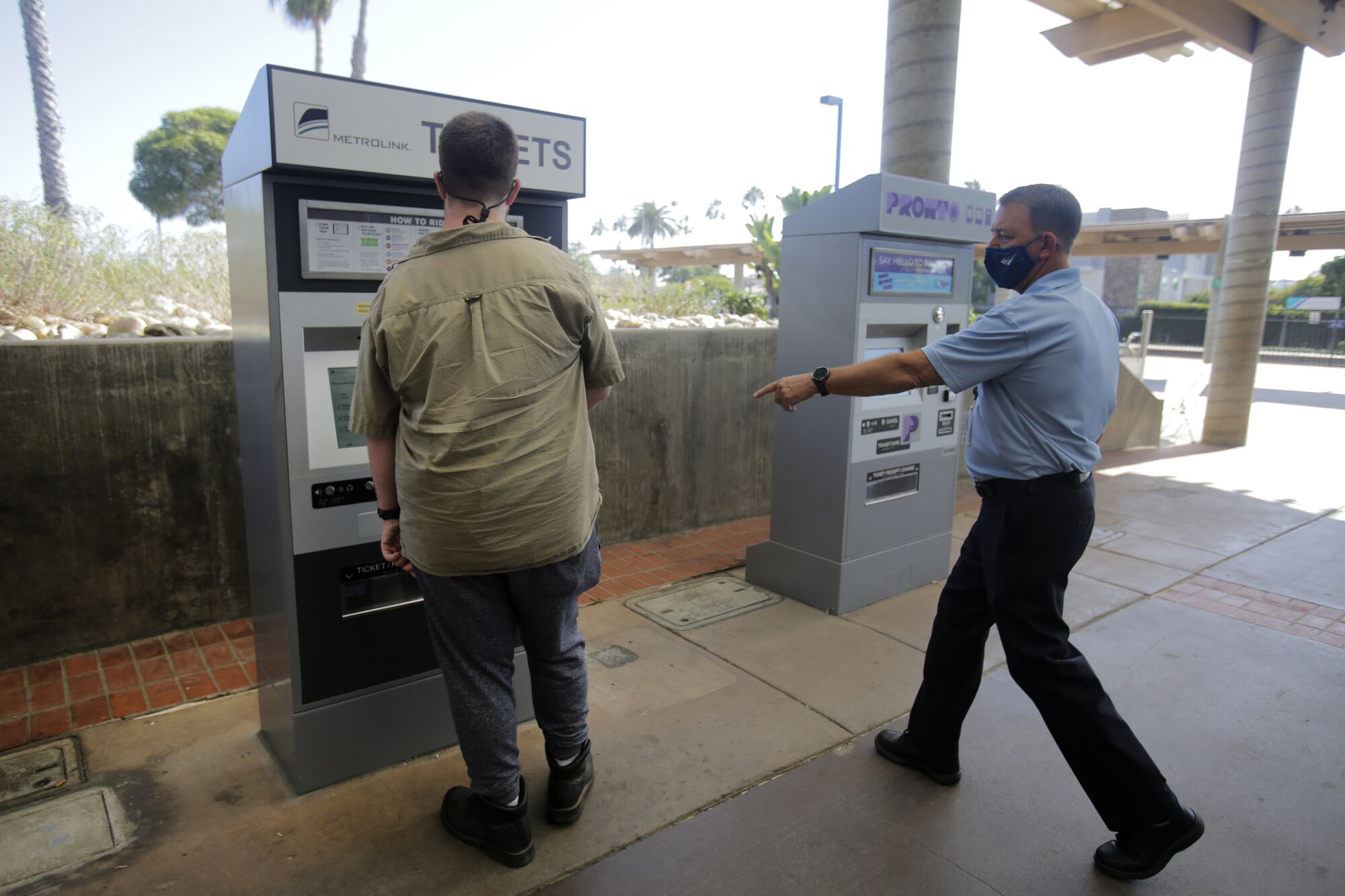 An Amtrak customer service representative, right, tells a passenger to heed the printed notice on a ticket machine.