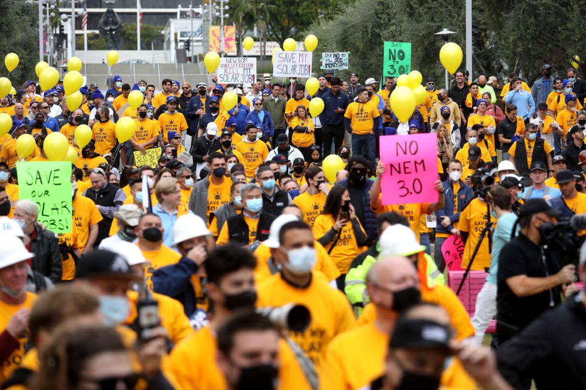 People in yellow shirts, some with yellow balloons and others holding placards, attend a rally 