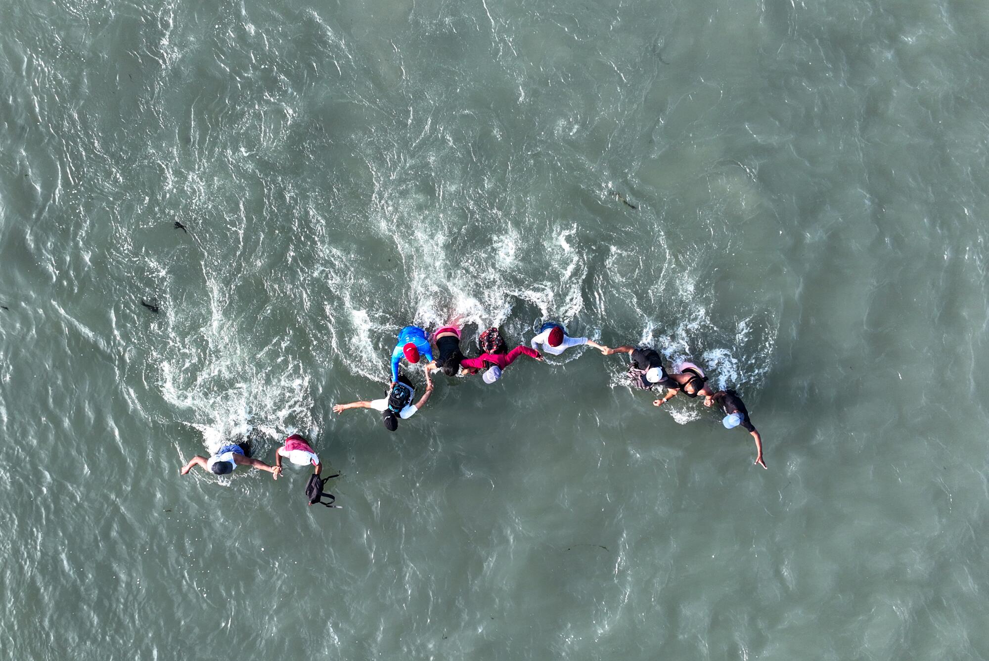  An overhead view of people walking in a line through water