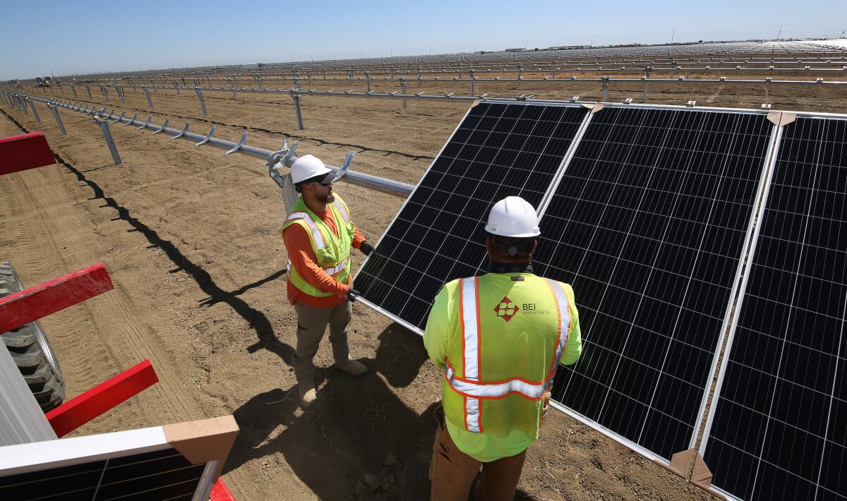 Michael Figueroa, left, places panels at the construction site of Westlands Solar Park in Kern County in 2021.