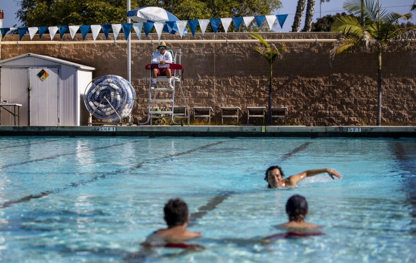 Swimmers in a public swimming pool near a lifeguard.