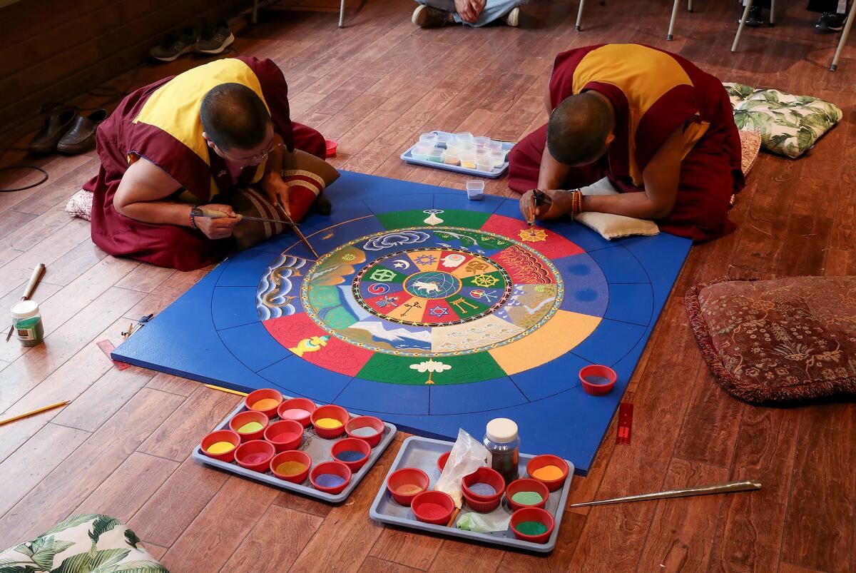 Drepung Gomang monks delicately work on a colorful world peace mandala at the Sawdust Festival Friday.