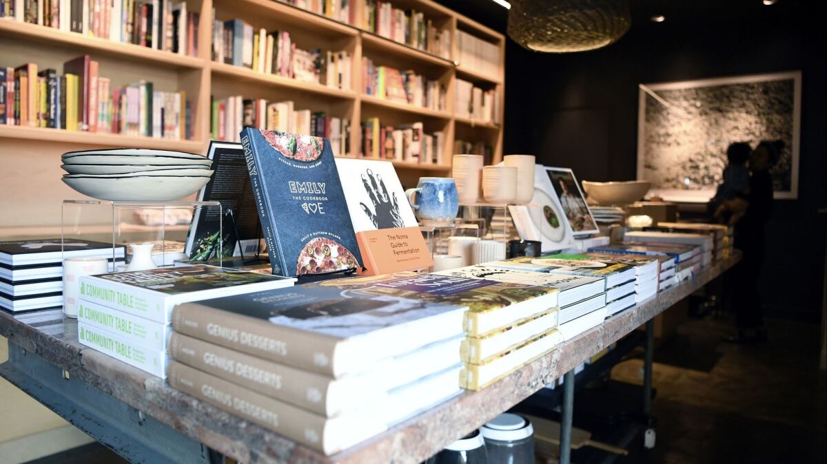 At Now Serving, shelves of cookbooks and a center island of ceramics and more cookbooks.