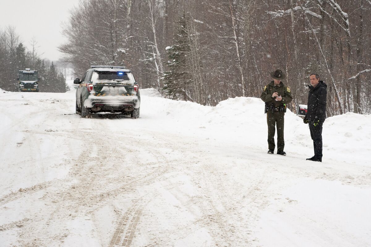 FILE — A Vermont State Trooper, center, speaks to a homeowner on Thursday, Jan. 8, 2018 near an area on Peacham Road, in Barnet, Vt., where the body of Gregory Davis was found. Federal prosecutors say a conspiracy that resulted in the murder of Gregory Davis grew out of a financial dispute between him and one of the men now charged with arranging to have him killed. In a Monday, May 30, 2022 filing, prosecutors said that Davis had been threatening to go to the FBI with information that Serhat Gumrukcu was defrauding him in a multi-million dollar oil deal. (Dana Gray/Caledonian-Record via AP, File)