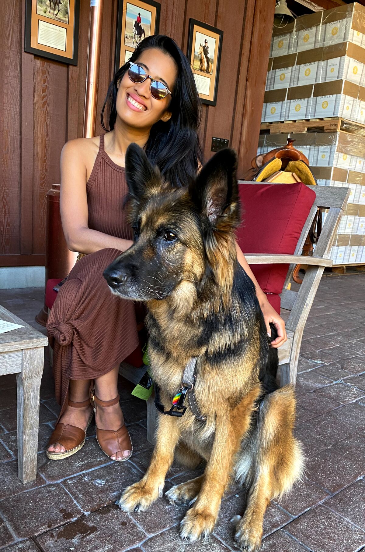 A woman smiles as she puts her arm around a large dog 