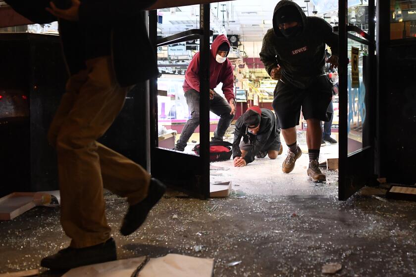 LOS ANGELES, CALIFORNIA MAY 29, 2020-Looters run from a jewelry store as LAPD officers approach in Downtown Los Angeles Friday. Protestors marched across the nation after the death of George Floyd. (Wally Skalij/Los Angeles Times)
