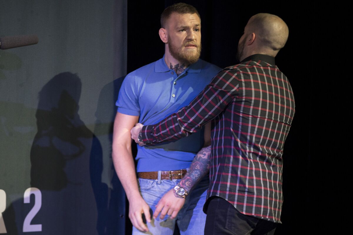 Conor McGregor is held back from an altercation between his team and that of opponent Nate Diaz during a news conference on Aug. 17.