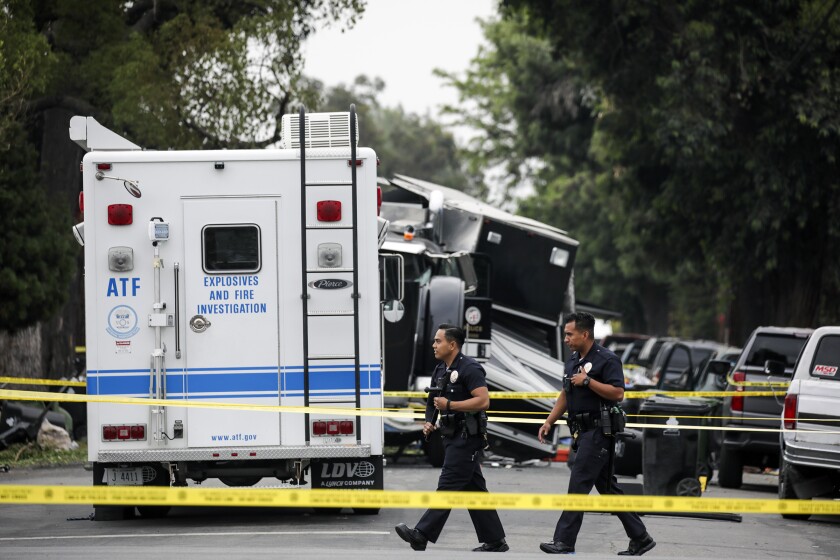 Police officers walk near an ATF vehicle behind crime-scene tape
