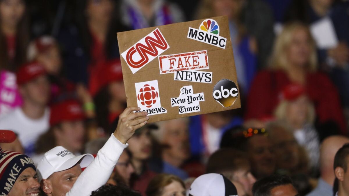 An audience member holds a "fake news" sign during a Donald Trump campaign rally in Washington Township, Michigan, on April 28, 2018.