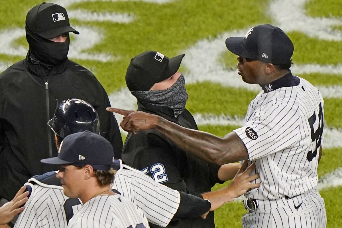 Third base umpire Jansen Visconti, center, restrains New York Yankees relief pitcher Aroldis Chapman, right, after the Tampa Bay Rays and Yankees traded words after the Yankees' 5-3 victory in a baseball game, Tuesday, Sept. 1, 2020, at Yankee Stadium in New York. The altercation ensued after Chapman threw a high pitch at Rays pinch hitter Michael Brosseau in the final at-bat of the game. (AP Photo/Kathy Willens)