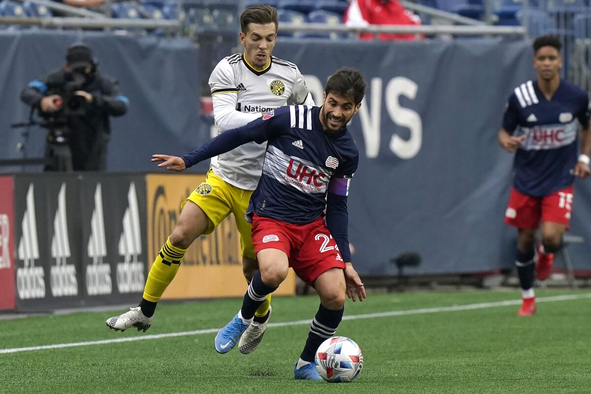 The Columbus Crew's Pedro Santos, left, puts pressure on New England Revolution's Carles Gil, center, May 16