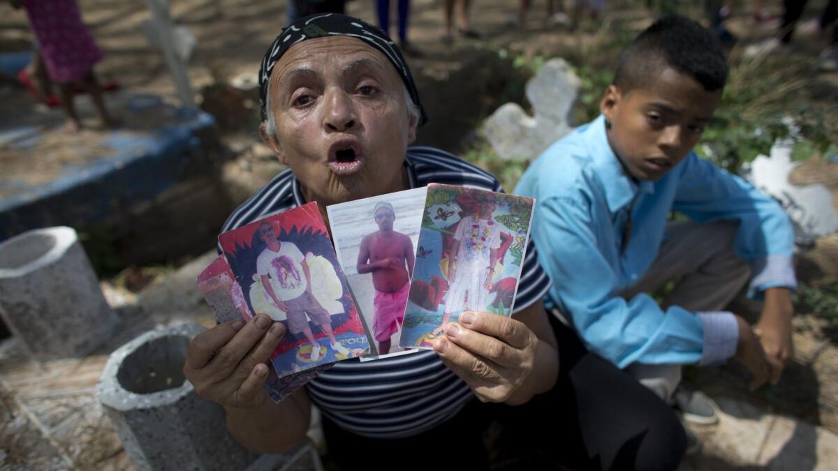Yajaira Rojas shows photos of her late son Alix Eduardo Diaz during his funeral Friday at the Municipal Cemetery of Valencia, Venezuela.