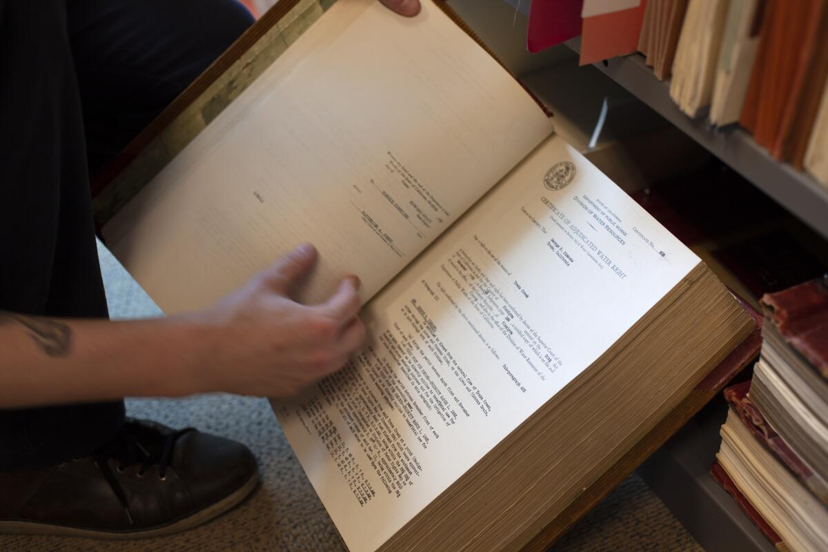 Matthew Jay, analyst at the State Water Resources Control Board, holds a volume of adjudicated water rights certificates. 