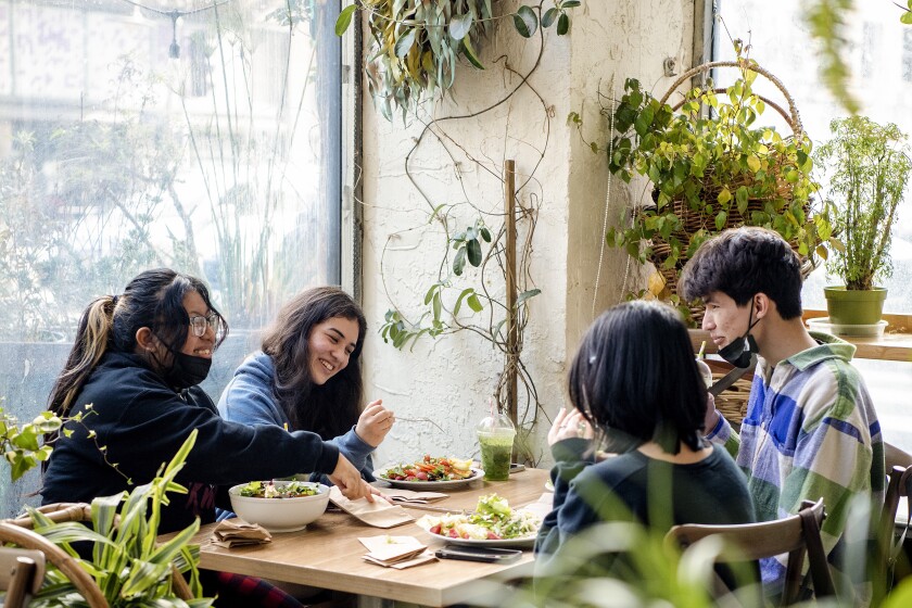 Four customers sit at a restaurant table, eating and laughing.