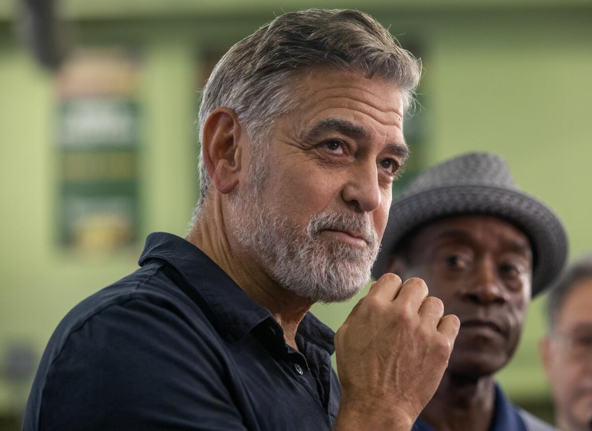 George Clooney holds his fist in front of his chin and looks up.