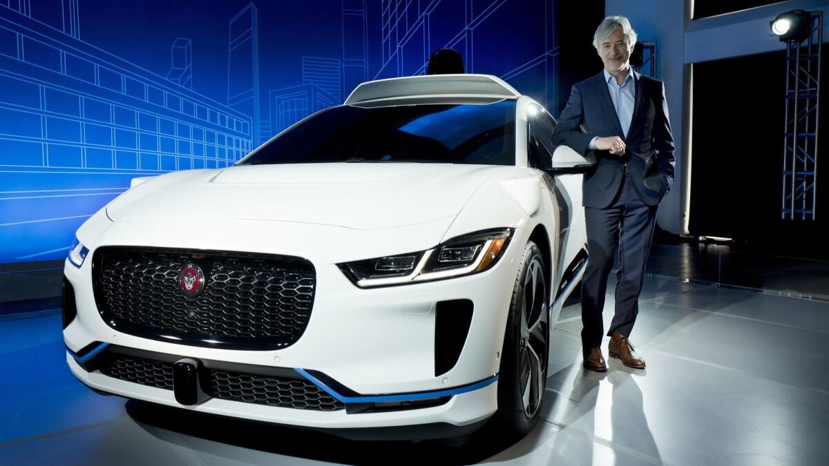 John Krafcik, the chief executive of Waymo, stands with the Jaguar I-Pace. Waymo will buy up to 20,000 of the electric vehicles to help realize its vision for a robotic ride-hailing service.