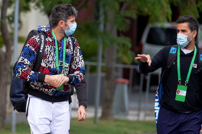 Italian tennis player Simone Bolelli, left, and Argentina's Maximo Gonzalez are escorted to their training session in Melbourne, Australia, Monday, Jan. 18, 2021. The number of players in hard quarantine swelled to 72 ahead of the Australian Open after a fifth positive coronavirus test was returned from the charter flights bringing players, coaches, officials and media to Melbourne for the season-opening tennis major. (Luis Ascui/AAP Image via AP)