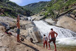 SAN DIEGO, CA-APRIL 16: Visitors look-out over a waterfall at Three Sisters Falls on Sunday, April 16, 2023 in the Cleveland National Forest outside of Julian. The Waterfall is brimming with water due to the recent rains which have swollen the creeks that feed the falls. It's a popular Four Mile out-and-back trail that is considered moderately challenging.(Photo by Sandy Huffaker for The San Diego Union-Tribune)