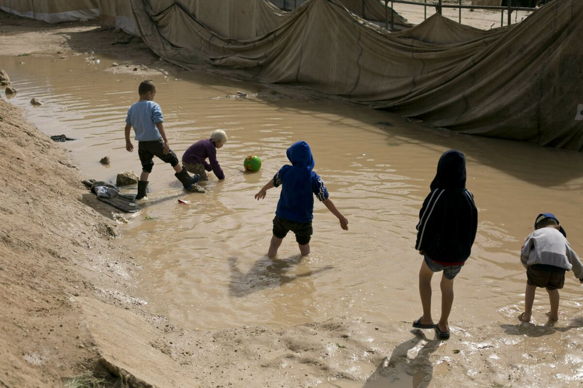 FILE - In this March 31, 2019 file photo, children play in a mud puddle in the section for foreign families at Al-Hol camp in Hasakeh province, Syria. At least eight children under the age of five have died in recent days from health problems linked to the dire conditions in a camp in northern Syria housing tens of thousands of female supporters of the Islamic State group and their children, the U.N. said Thursday, Aug. 13,2020. (AP Photo/Maya Alleruzzo, File)