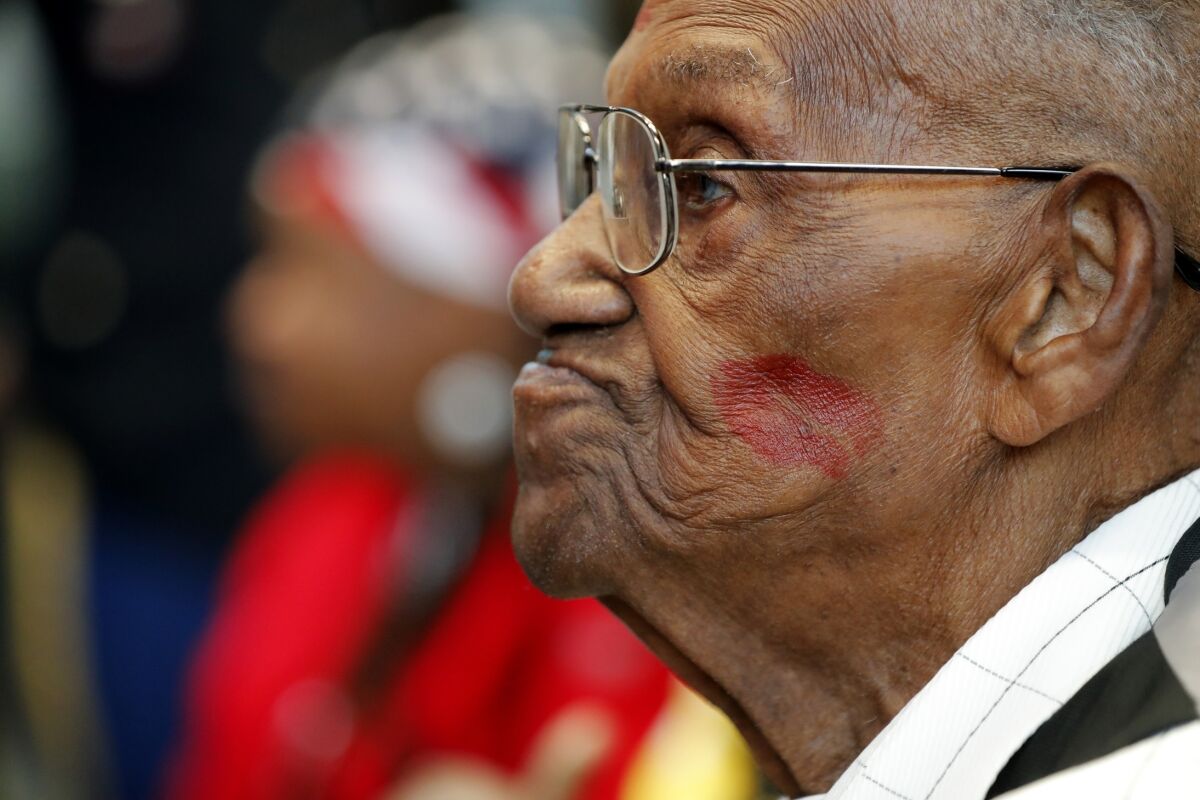 FILE-World War II veteran Lawrence Brooks sports a lipstick kiss on his cheek, planted by a member of the singing group Victory Belles, as he celebrates his 110th birthday at the National World War II Museum in New Orleans, Thursday, Sept. 12, 2019. The oldest World War II veteran in the United States has died at the age of 112. Lawrence N. Brooks died Wednesday, Jan. 5, 2022 in New Orleans. His death was announced by the National World War II Museum and confirmed by his daughter. (AP Photo/Gerald Herbert, File)