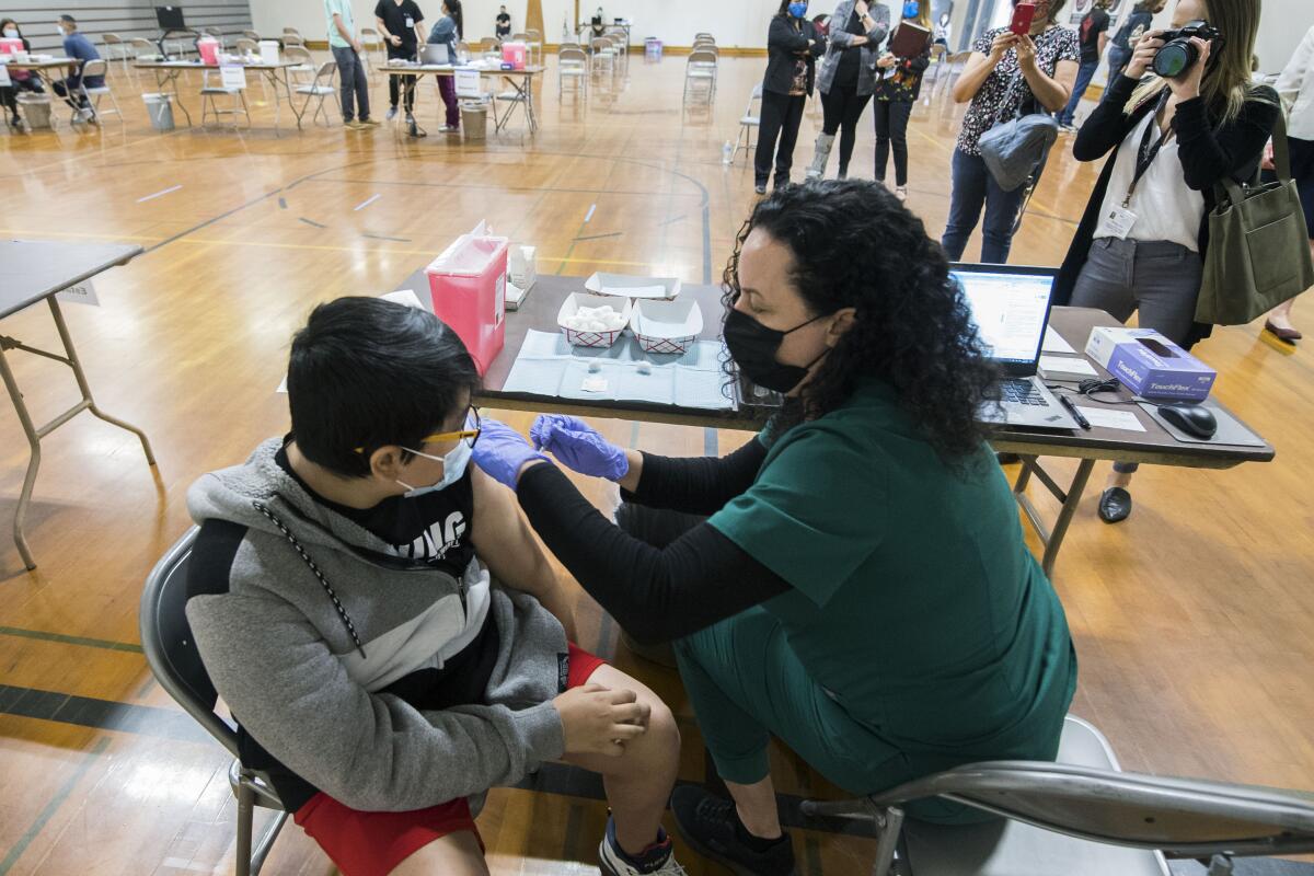 Nurse Jessica Lipscomb gives Miguel Castro, 13, of Brentwood, the Pfizer COVID-19 vaccine in the Antioch Middle School gym in Antioch, Calif., May 19, 2021. In partnership with Kaiser Permanente and the Contra Costa Office of Education, the Contra Costa Health Services have started school-based COVID-19 vaccination clinics. While coronavirus cases remain low in California, the nation's most populous state has recently seen hospitalizations creep back up slightly. (Doug Duran/Bay Area News Group via AP)