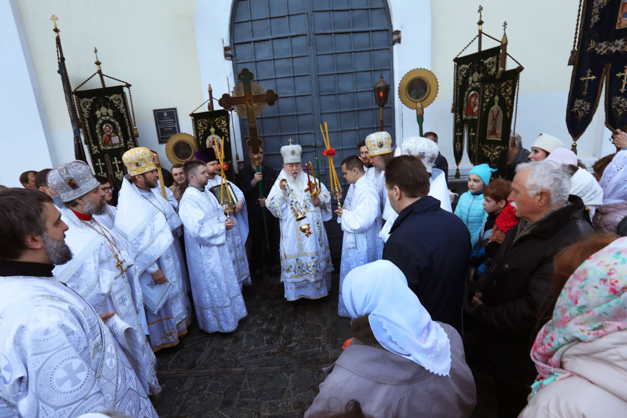Men in white robes and hats with worshipers at church 