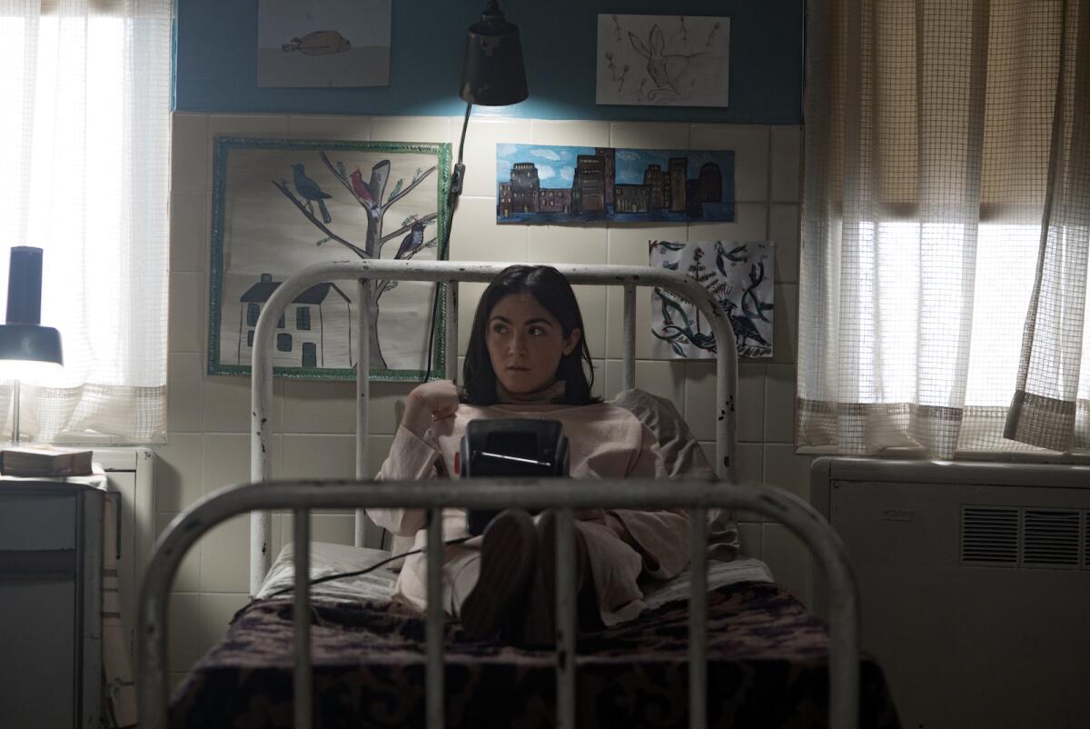 A young woman sitting up on a bed in the movie "Orphan: First Kill."
