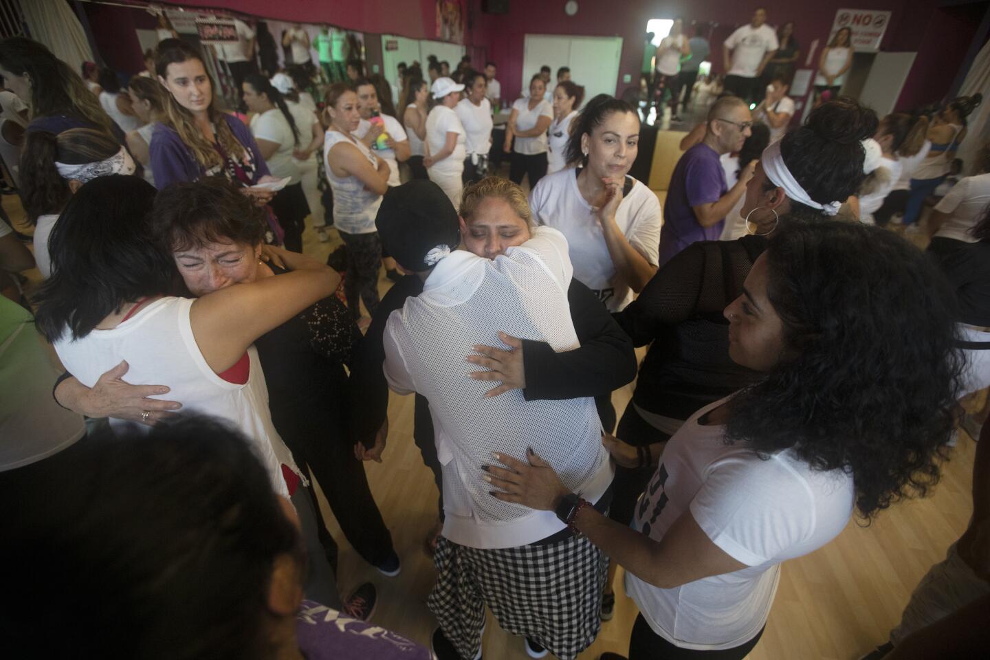 People surround and hug Keyla’s mother, Lorena Pimentel de Salazar, middle, at a Zumba class fundraiser at Dancing Angel’z Blvd in San Jose.