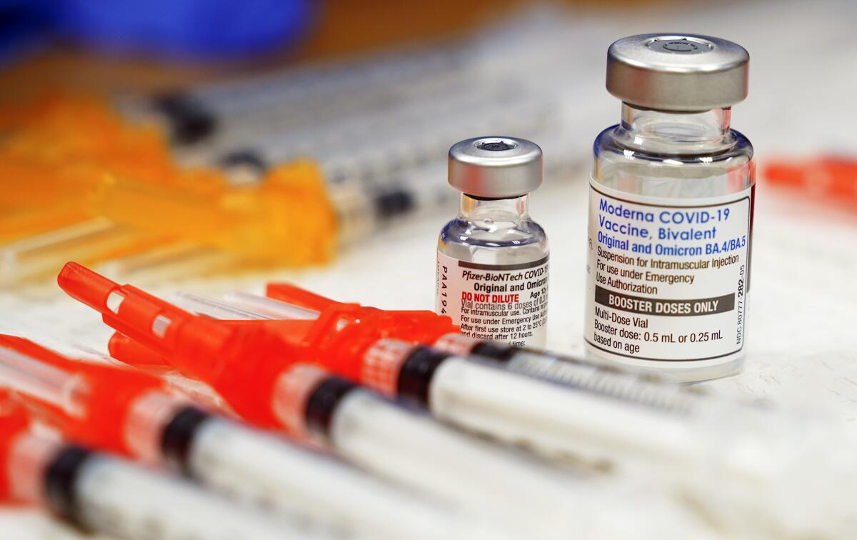  Syringes with COVID-19 vaccines lined up next to vials.