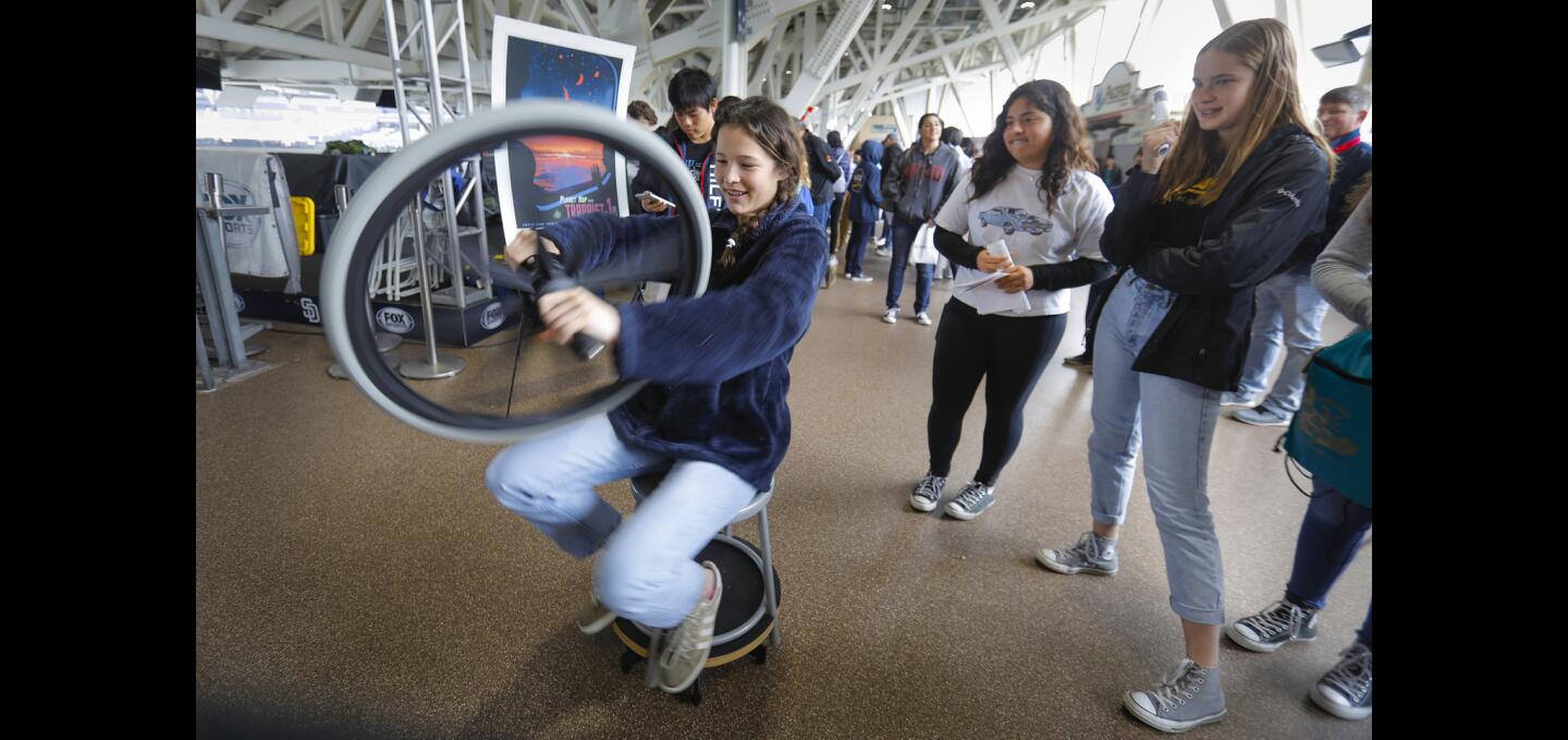 Jesse Hill de La Mesa, estudiante de octavo grado, visitó el puesto del Departamento de Física de la UC San Diego durante el Festival Anual de Ciencia e Ingeniería de San Diego en Petco Park. Se sentó en un taburete que se mueve libremente y sostuvo un giroscopio de neumático de bicicleta giratorio que, al cambiar de ángulo, hizo que se girara mientras se sentaba.