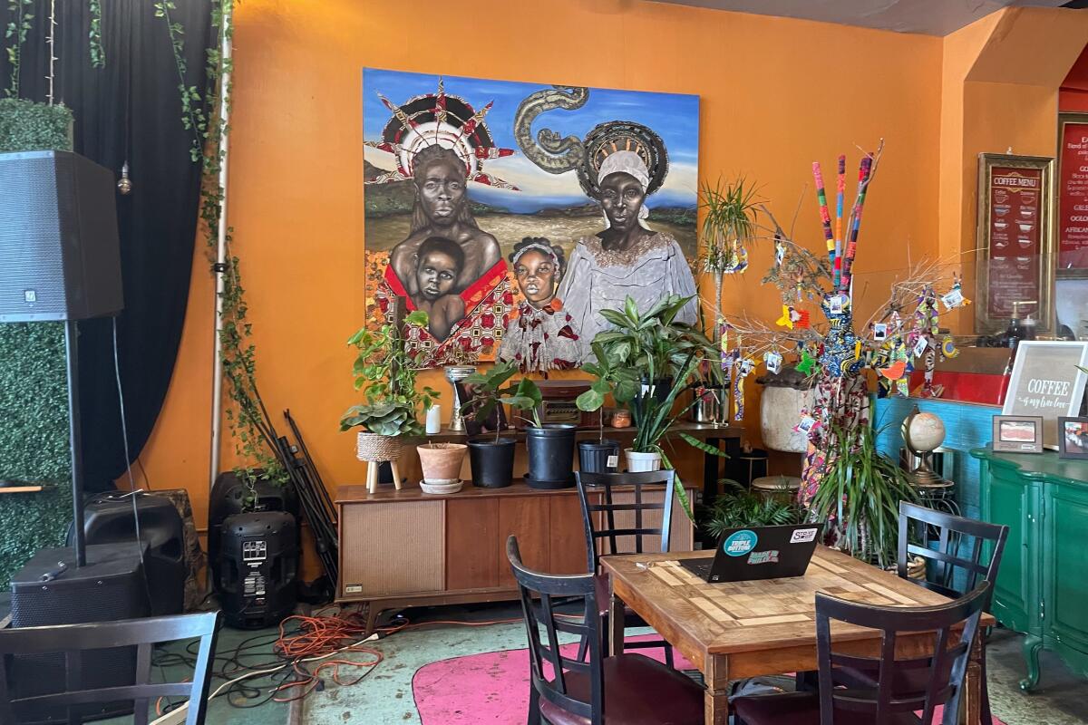 An orange wall with a colorful painting inside a cozy-looking coffee shop