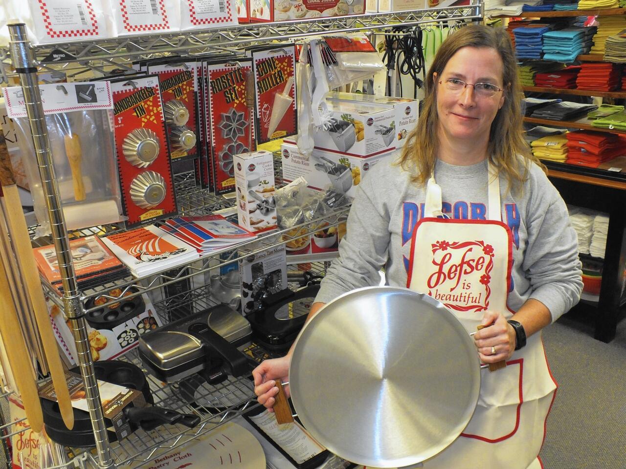 Wearing an apron that demonstrates her devotion to lefse, Julie Spilde holds one of the Norwegian-style pans sold in her Decorah kitchen store.