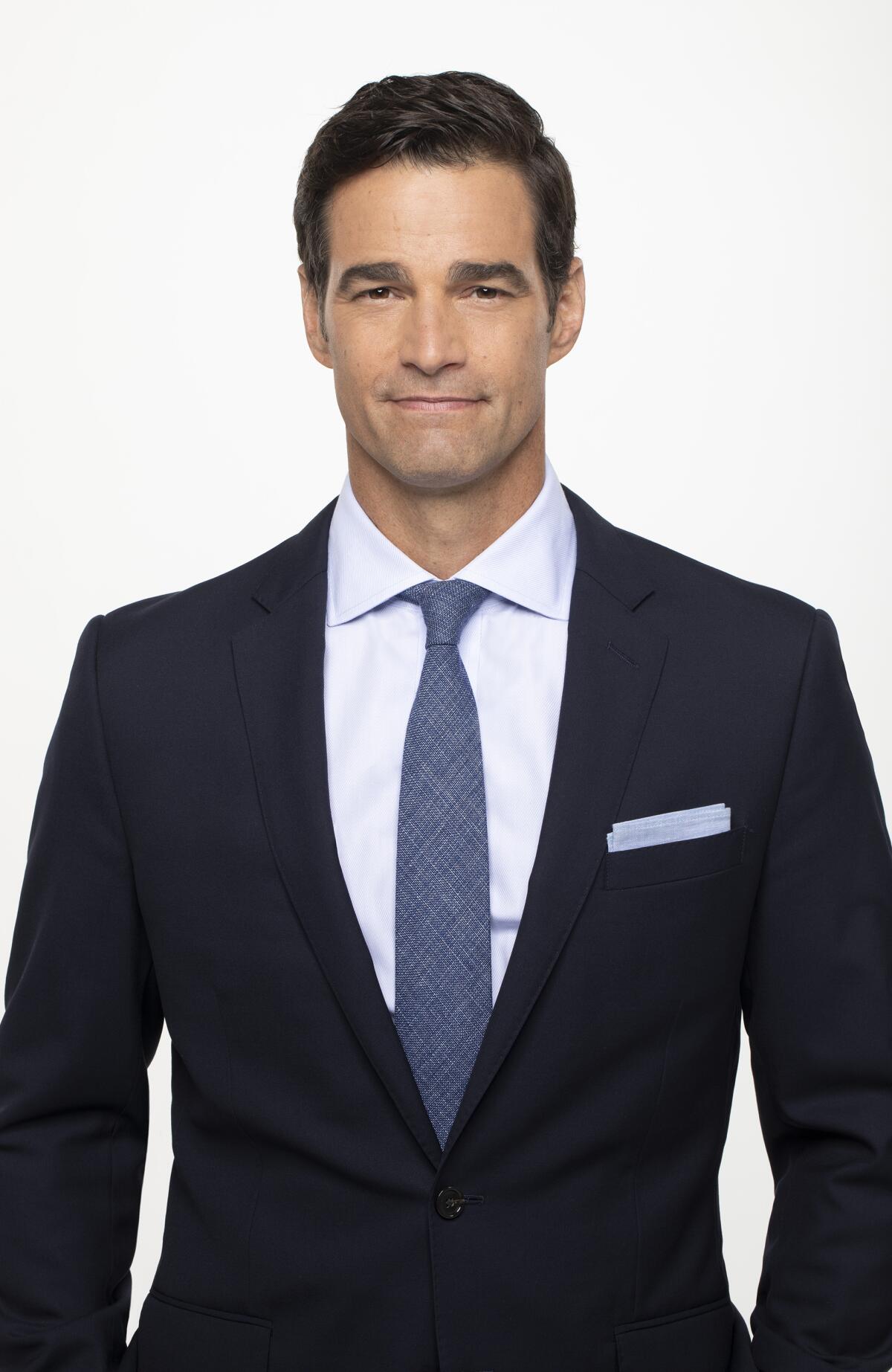 Rob Marciano poses in a dark suit with blue tie.