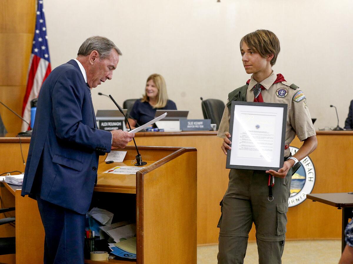 Mayor Bob Whalen hands Eagle Scout Mason Bruderer a proclamation.