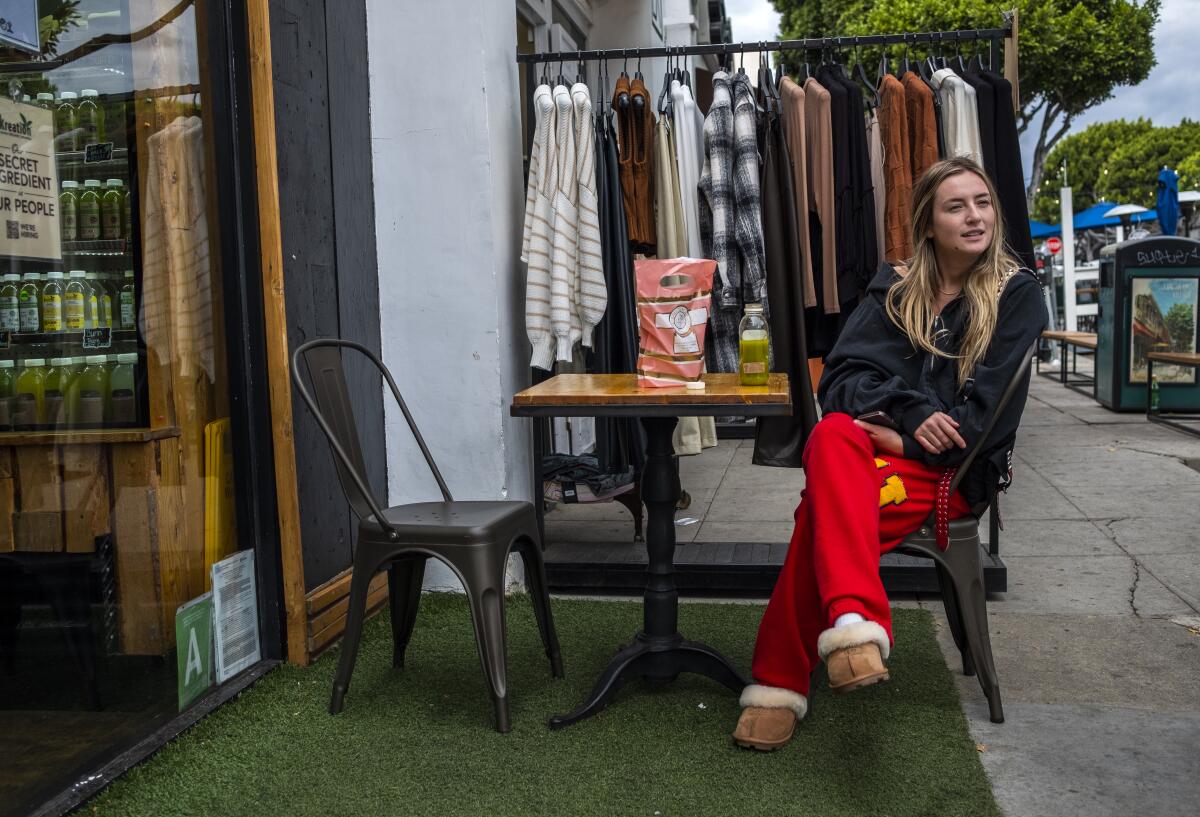 A woman sits outside a shop with a juice