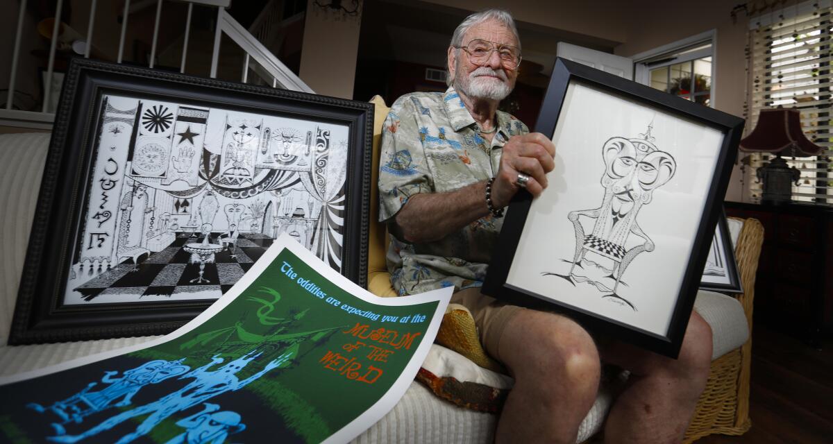 Rolly Crump holds drawings, with others spread out beside him.