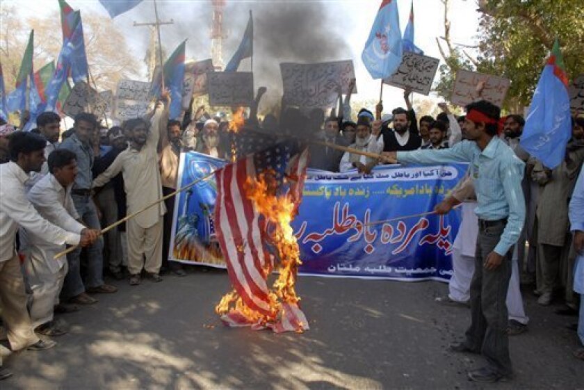 Pakistani protesters burn a U.S. flag before a banner reads 'Down with America rally' to condemn a suspected American missile strike at Taliban and militants' hideouts in Pakistani tribal areas along Afghanistan in Multan, Pakistan on Thursday, Nov. 20, 2008. Pakistan summoned the U.S. ambassador Thursday to protest a suspected American missile strike deep inside its territory as militants threatened revenge attacks unless the cross-border raids stop. (AP Photo/Khalid Tanveer)