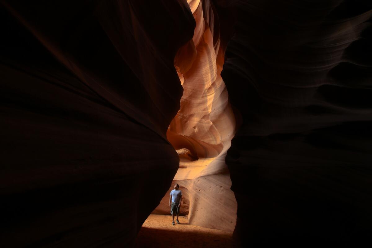 Navajo guide Raymond Chee stands in the opening to Antelope Canyon near Page, Ariz. The canyon, part of Lake Powell Navajo Tribal Park, is carved in large part by monsoon runoff and is up to 120 feet deep with just a ribbon of blue sky above.