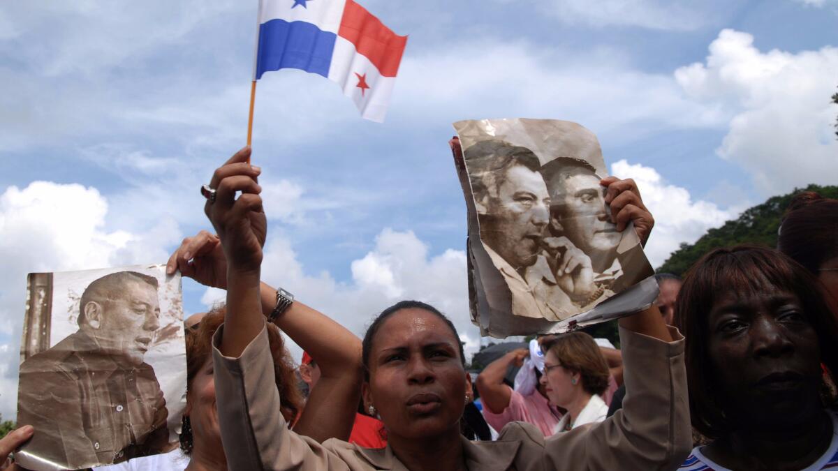 Panamanians hold up photos of President Martin Torrijos and his father, former Gen. Omar Torrijos, and Panama's flag at a ceremony marking the beginning of the Panama Canal expansion.