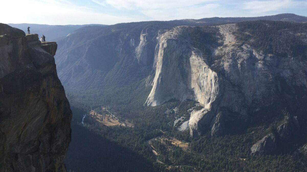 A couple on their wedding day are seen being photographed at Taft Point in California's Yosemite National Park in September. A Yosemite park official said Thursday that two visitors have died in a fall from the popular overlook.