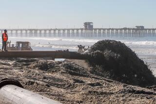 SAN DIEGO, CA October 19th, 2018 | Sand flies out of a pipe along the beach just north of the Oceanside Pier (background) on Friday in Oceanside, California. A dredge (not pictured) is removing sand from the entrance to Oceanside Harbor and the sand is being used to replenish the beach. | (Eduardo Contreras / The San Diego Union-Tribune)