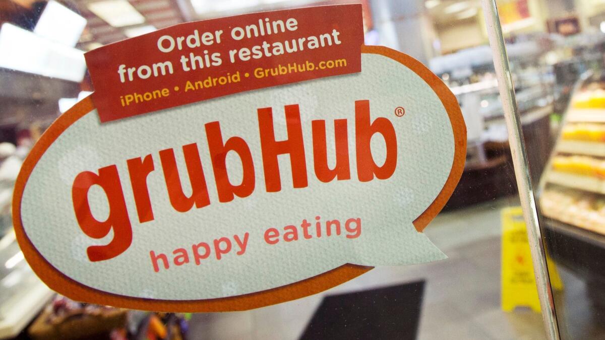 A sign for GrubHub is displayed on the door of a New York restaurant.