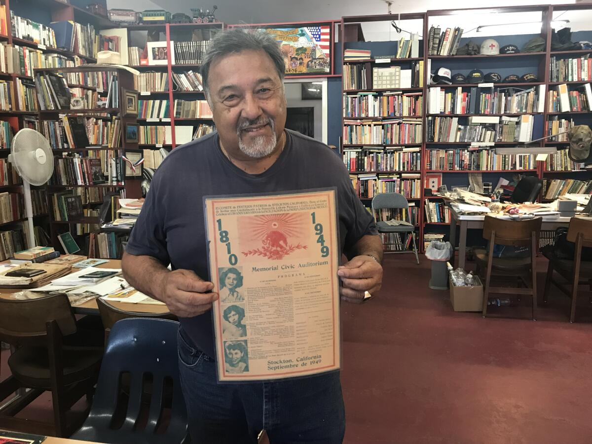 Richard Soto holds an item from his collection — a laminated program from a 1949 event featuring a young Dolores Huerta (then known as Dolores Fernandez) — at his Chicano Research Center in Stockton, Calif.