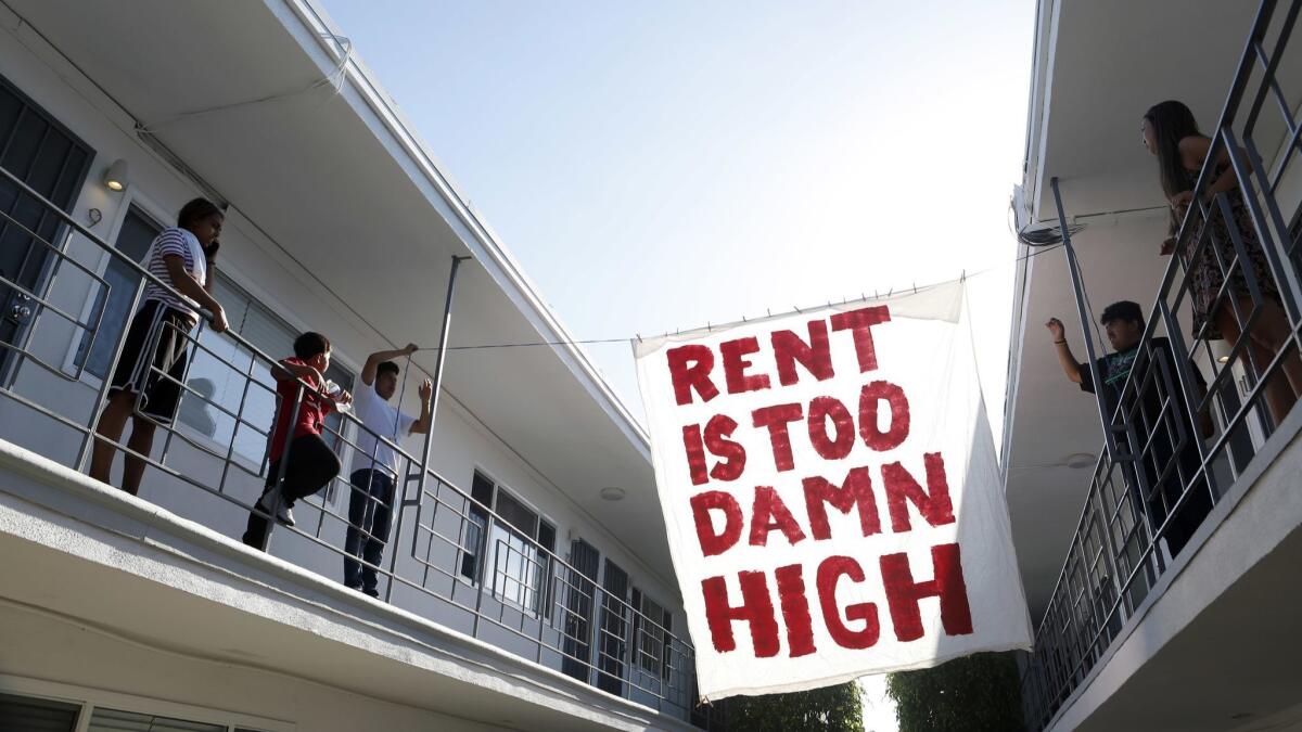 Organizers with Housing Long Beach, a group pushing for rent control and eviction protections, hang a sign in the courtyard of an apartment complex on Cedar Avenue.