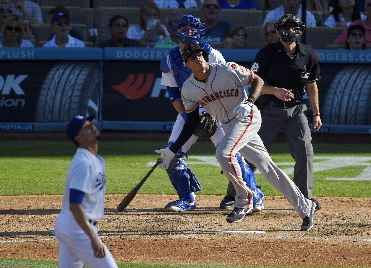 San Francisco's Justin Maxwell hits a two-run home run as Dodgers starting pitcher Carlos Frias, catcher Yasmani Grandal and home plate umpire Chris Guccione watch Saturday at Dodger Stadium.