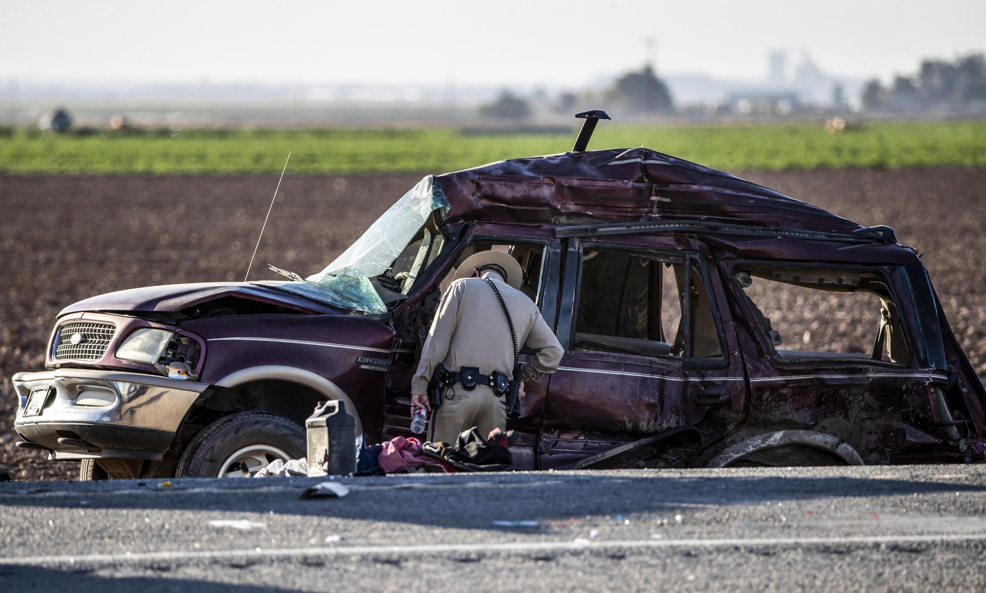 A CHP officer looks inside the mangled SUV involved in a fatal crash near the border