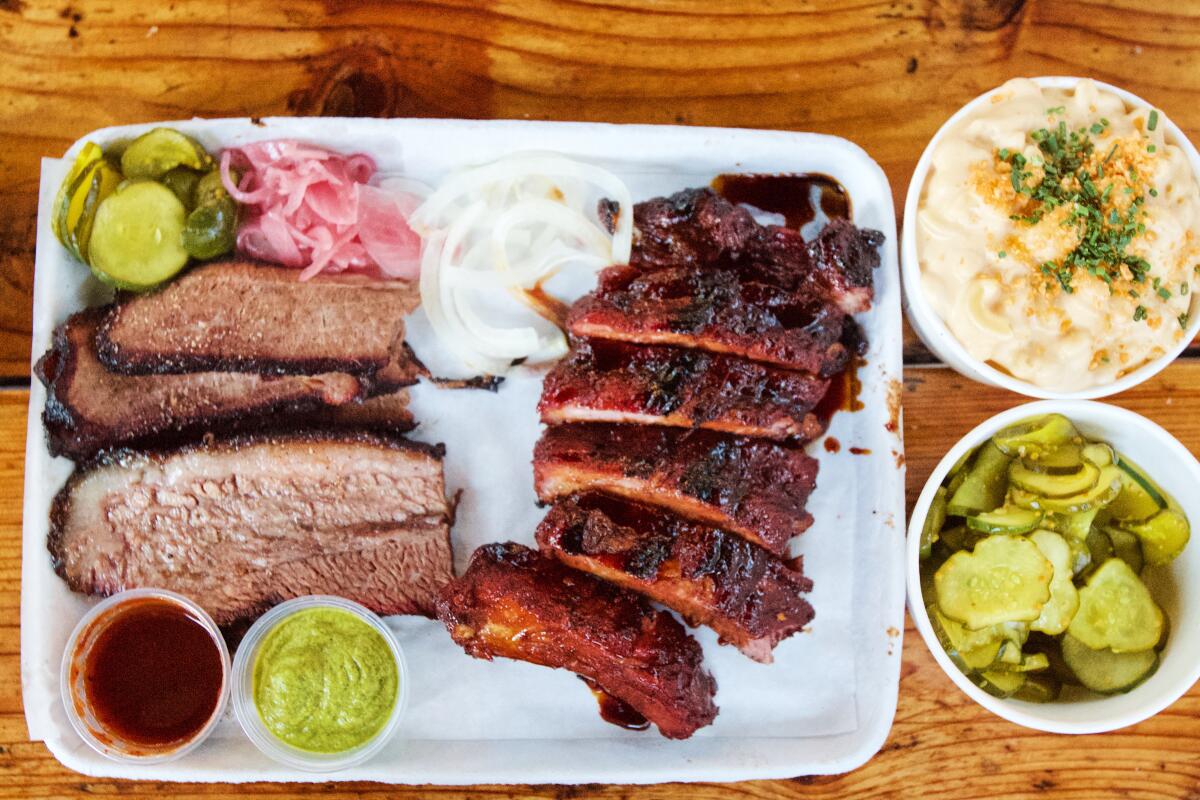 A paper barbecue tray of ribs, brisket, pickles, sauce and onions with mac and cheese from Maple Block Meat Co.