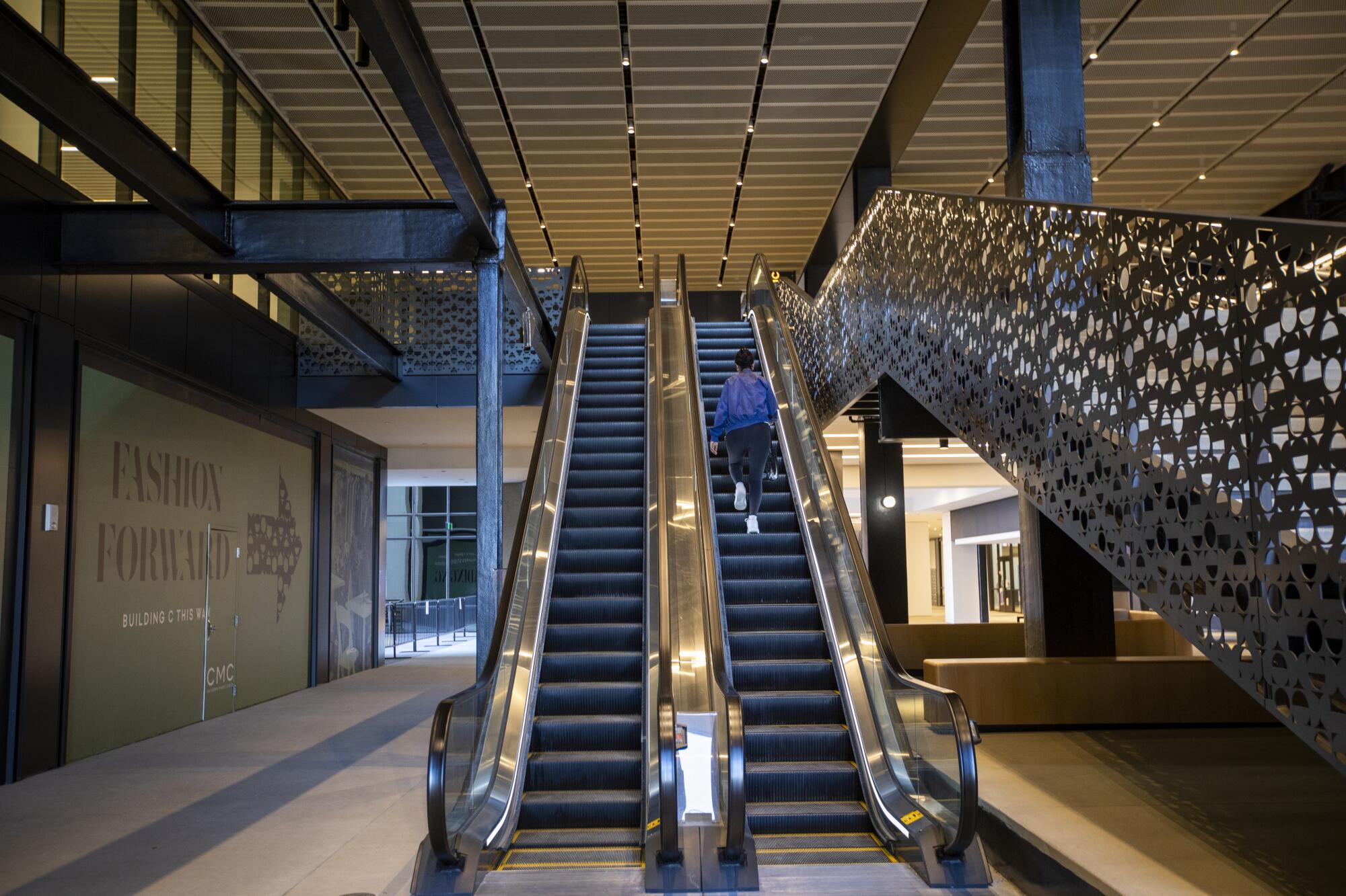 A woman walks up an escalator at the California Market Center in Los Angeles.